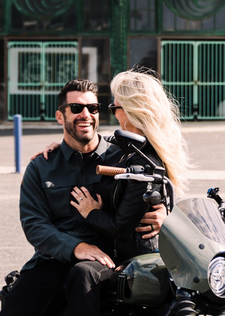 Scenic outdoor couples photography featuring a joyful moment with a pair of custom motorcycles parked alongside